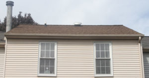 A new roof and the second story of a townhouse, seen from ground level. 